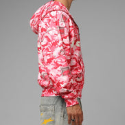 Person wearing a pink camouflage jacket on a gray background