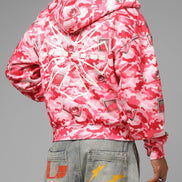 Person wearing a pink and white camouflage jacket on a gray background