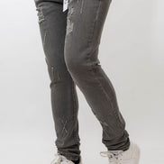Person wearing gray distressed jeans and white sneakers on a white background