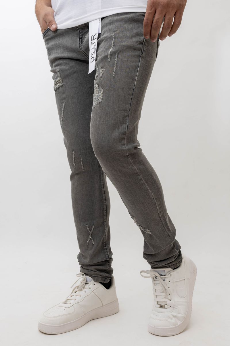 Person wearing gray distressed jeans and white sneakers on a white background