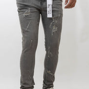 Person wearing distressed gray jeans with a brand label on a white background