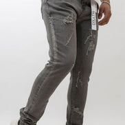 Person wearing gray distressed jeans with a white background