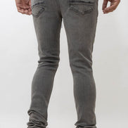 Person wearing gray jeans and white sneakers on a plain background