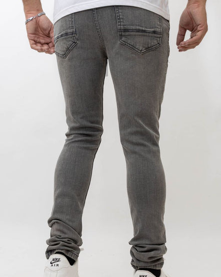 Person wearing gray jeans and white sneakers on a plain background