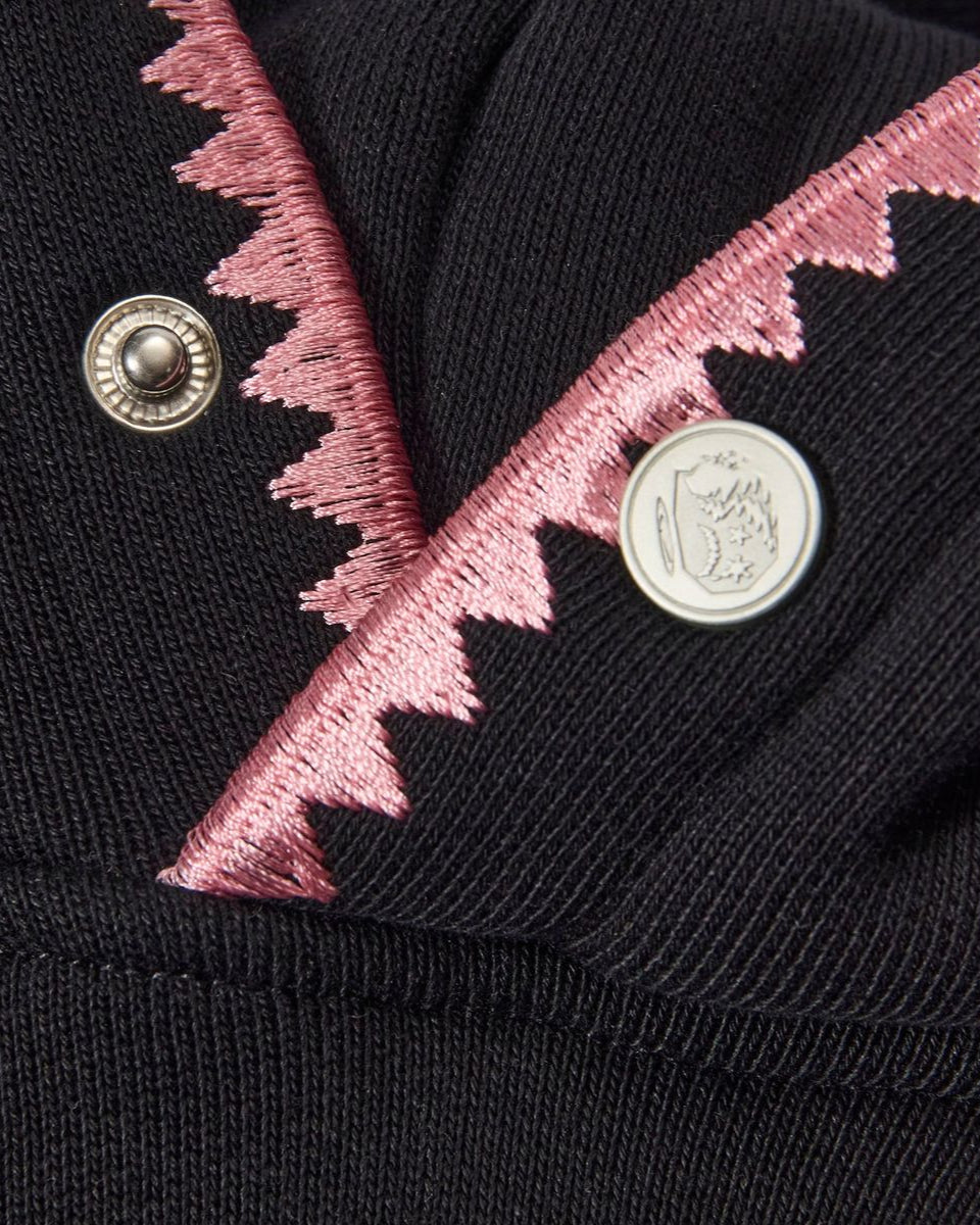 Black garment with pink embroidery and buttons