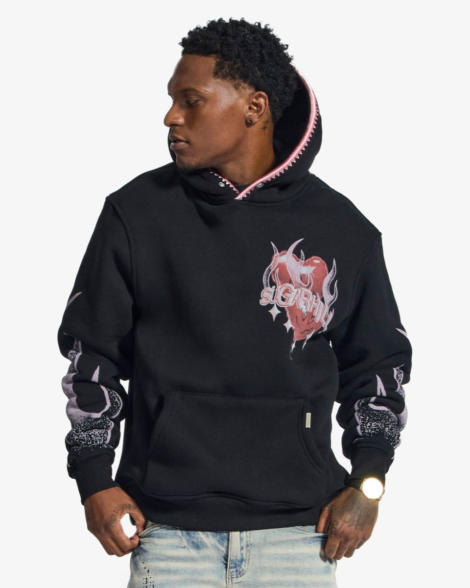 Man wearing a black hoodie with pink and white designs on a white background