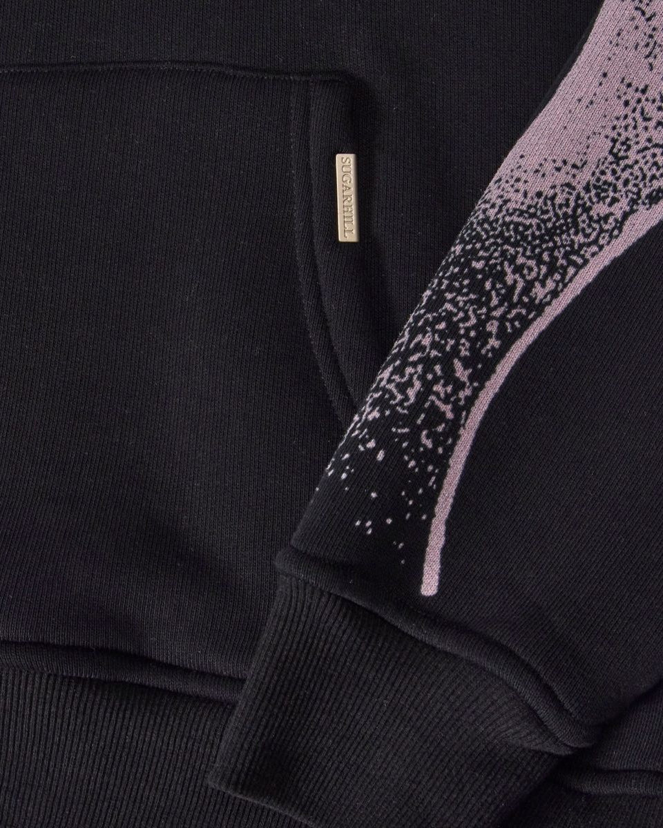 Black sweater with pink speckled pattern on sleeve, close-up view.