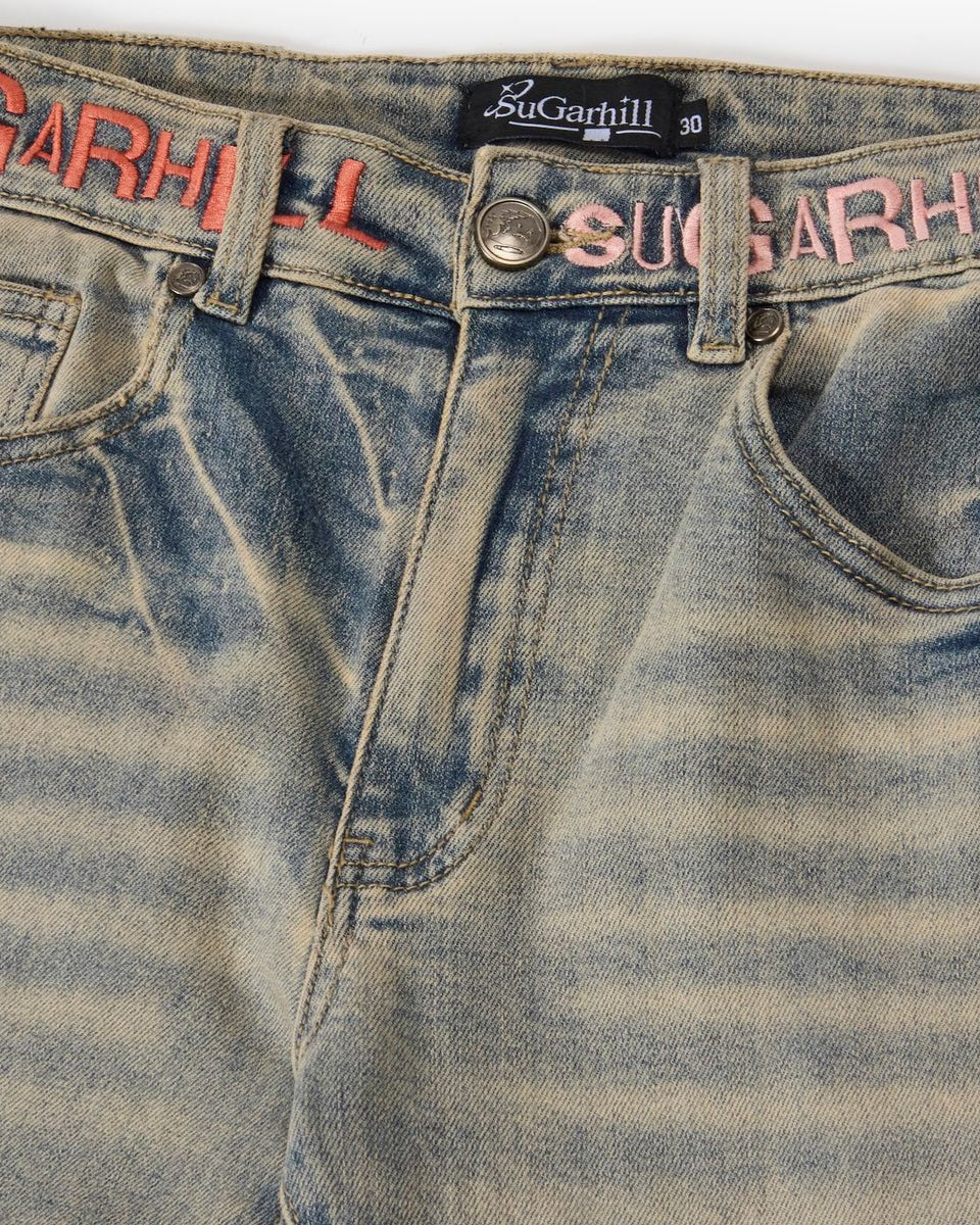 Close-up of a pair of blue jeans with 'SuGarhill' branding on a white background.
