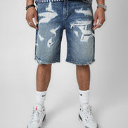 Person wearing distressed denim shorts with a plain background