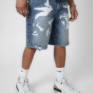 Person wearing distressed blue denim shorts with a white background