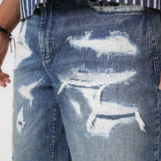 Distressed blue denim shorts worn with a striped shirt on a white background