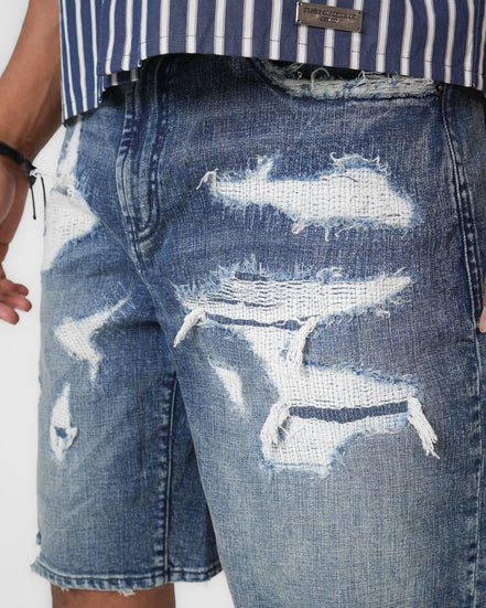 Distressed blue denim shorts worn with a striped shirt on a white background