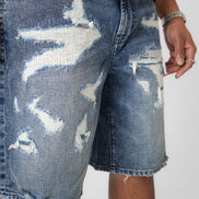 Distressed blue denim shorts on a plain background