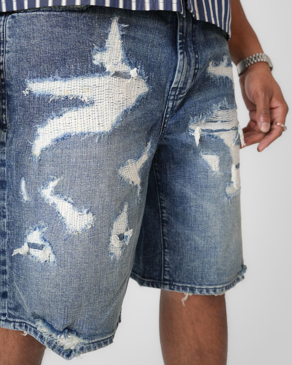 Distressed blue denim shorts on a plain background