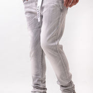 Person wearing light gray jeans with a subtle pattern and white sneakers on a white background