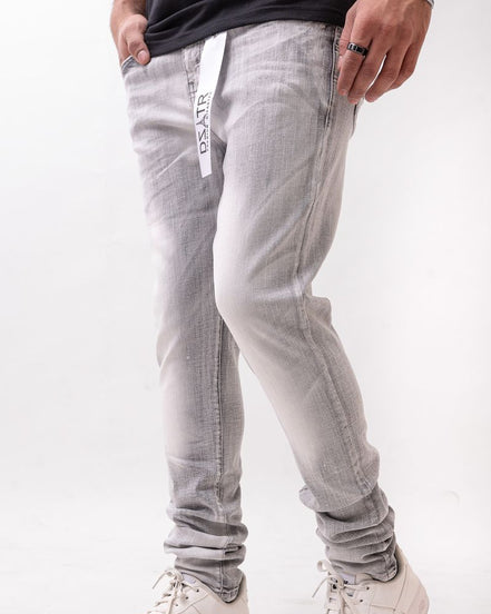 Person wearing light gray jeans with a subtle pattern and white sneakers on a white background