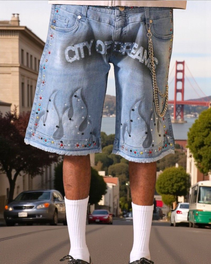 Person wearing denim shorts with 'CITY OF DENIM' text and penguin design, standing on a street with a cityscape background.