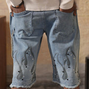 Person wearing light blue denim shorts with decorative elements, standing against a neutral background.