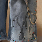 Denim shorts with embellishments and a gold chain on a blurred background