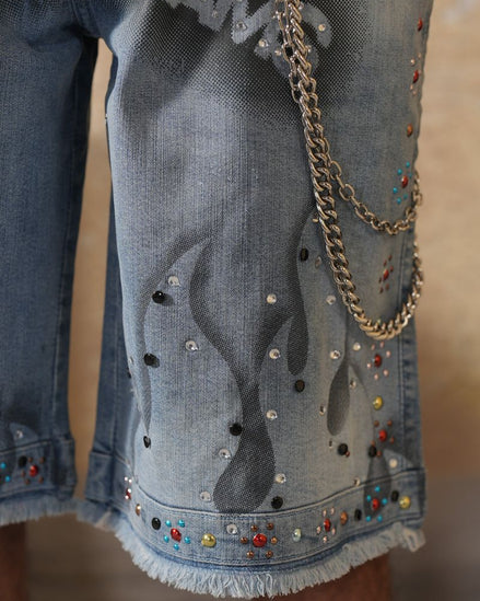 Denim shorts with embellishments and a gold chain on a blurred background