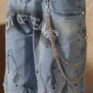 Denim shorts with embellishments and a chain detail on a plain background