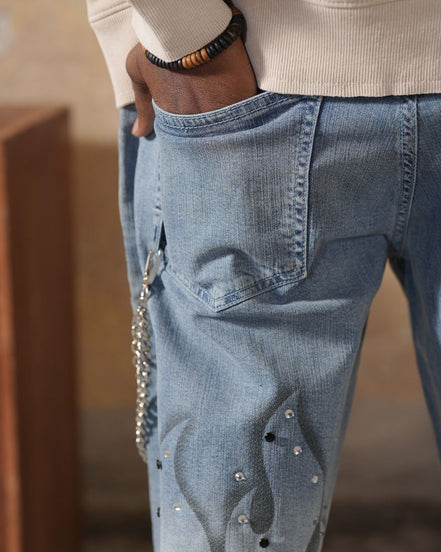 Close-up of blue jeans with decorative elements worn by a person.