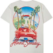 An off-white short-sleeve t-shirt shown from the back, featuring a large graphic print of a red convertible car, palm trees, a lighthouse, and the text 'Almost Someday' in red script.