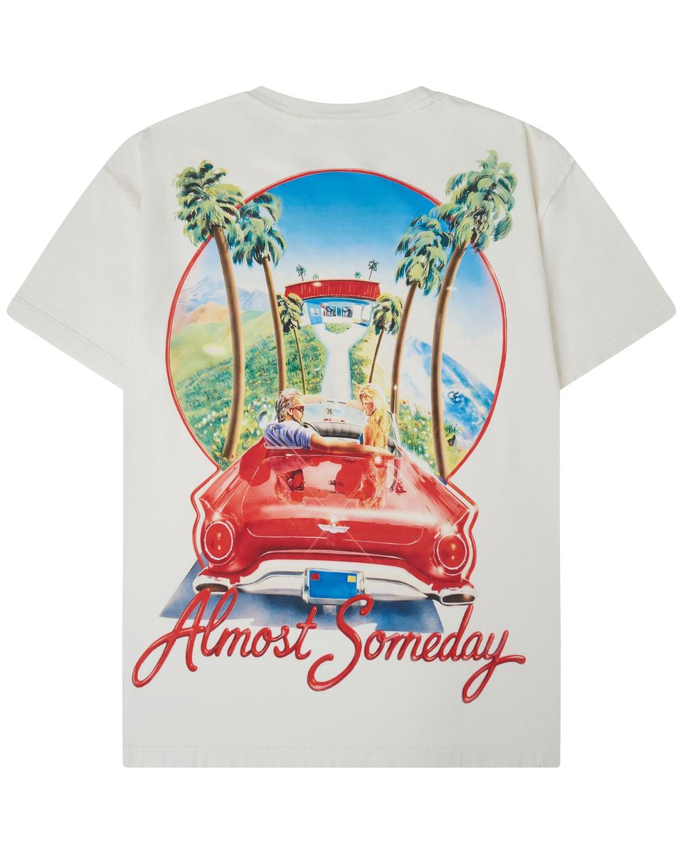 An off-white short-sleeve t-shirt shown from the back, featuring a large graphic print of a red convertible car, palm trees, a lighthouse, and the text 'Almost Someday' in red script.