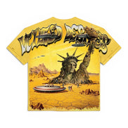 A yellow graphic t-shirt featuring a surreal desert scene with the Statue of Liberty rising from cracked earth, flying saucers, and the text 'Vtilted' in a stylized metallic font across the chest.