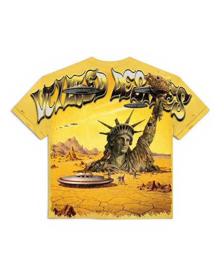 A yellow graphic t-shirt featuring a surreal desert scene with the Statue of Liberty rising from cracked earth, flying saucers, and the text 'Vtilted' in a stylized metallic font across the chest.