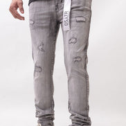 Person wearing gray distressed jeans with a visible brand tag on a white background
