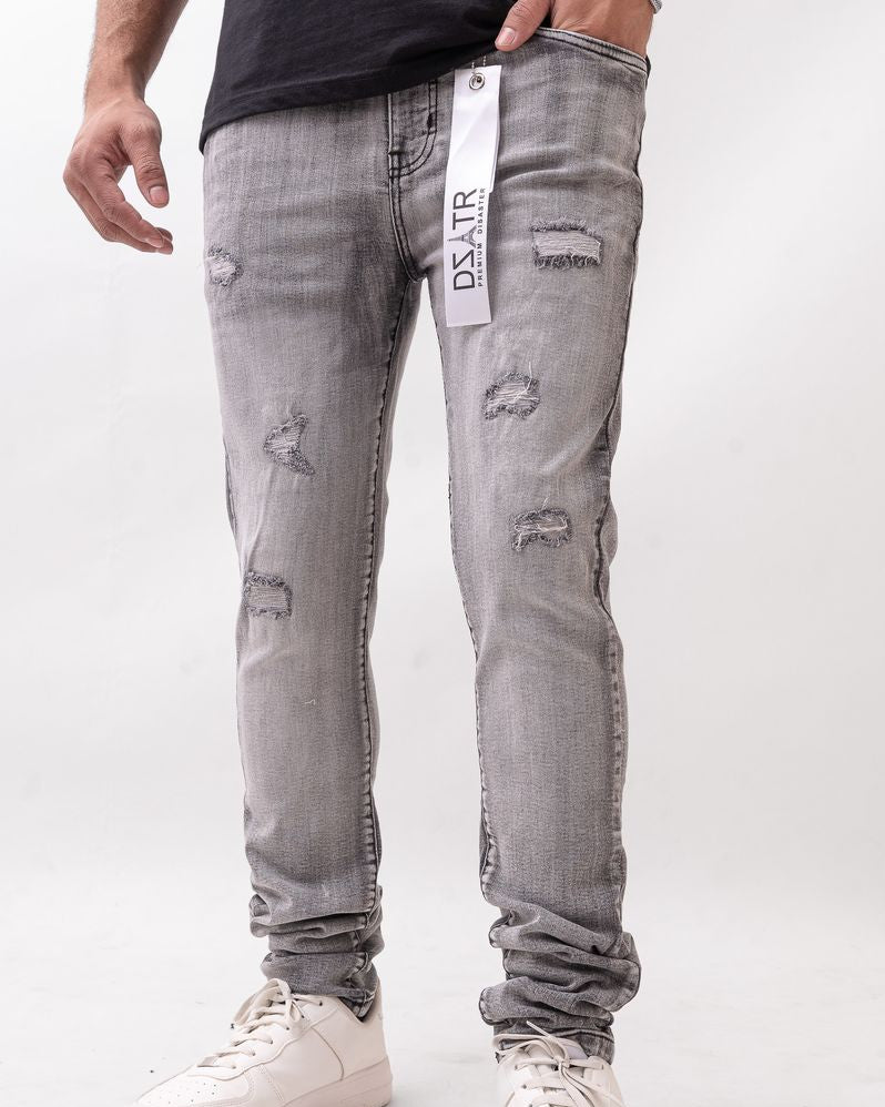 Person wearing gray distressed jeans with a visible brand tag on a white background