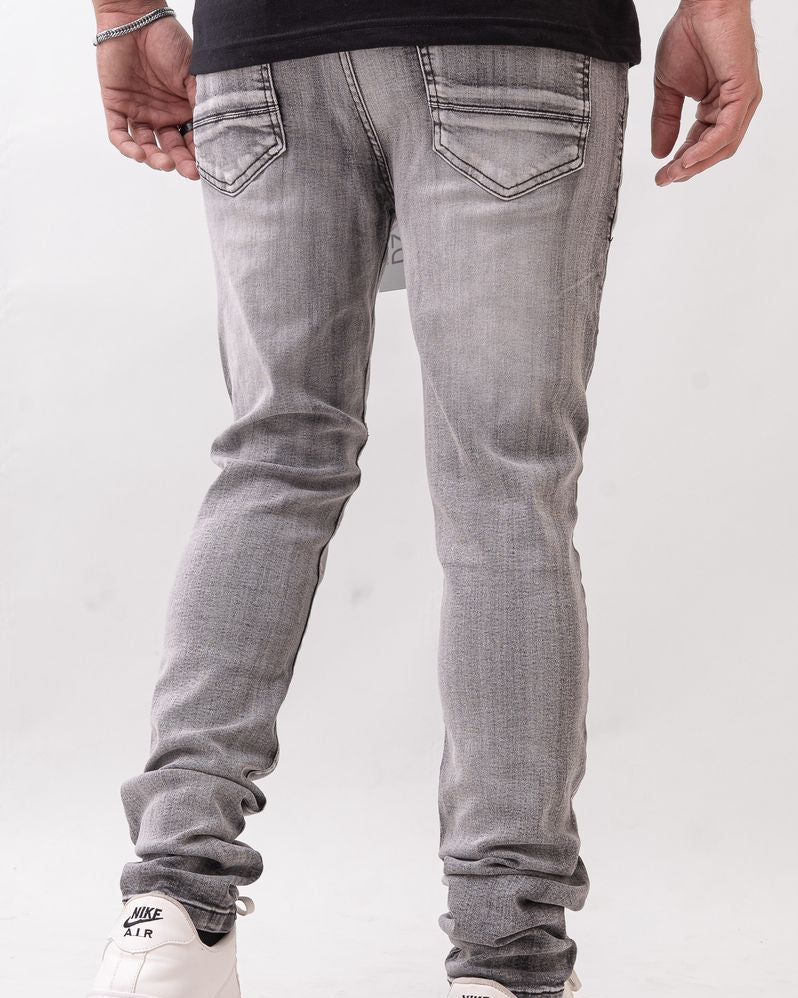 Person wearing gray jeans and white sneakers on a white background