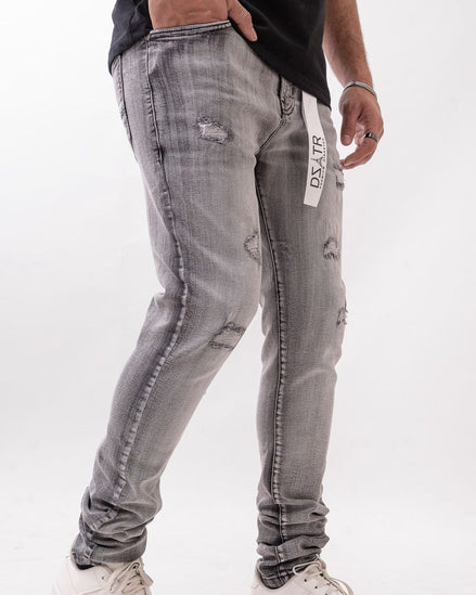 Person wearing gray distressed jeans with a white background