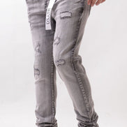 Person wearing gray distressed jeans with a white background
