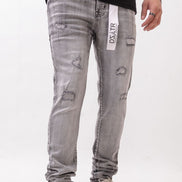 Person wearing gray distressed jeans with a brand label on a white background