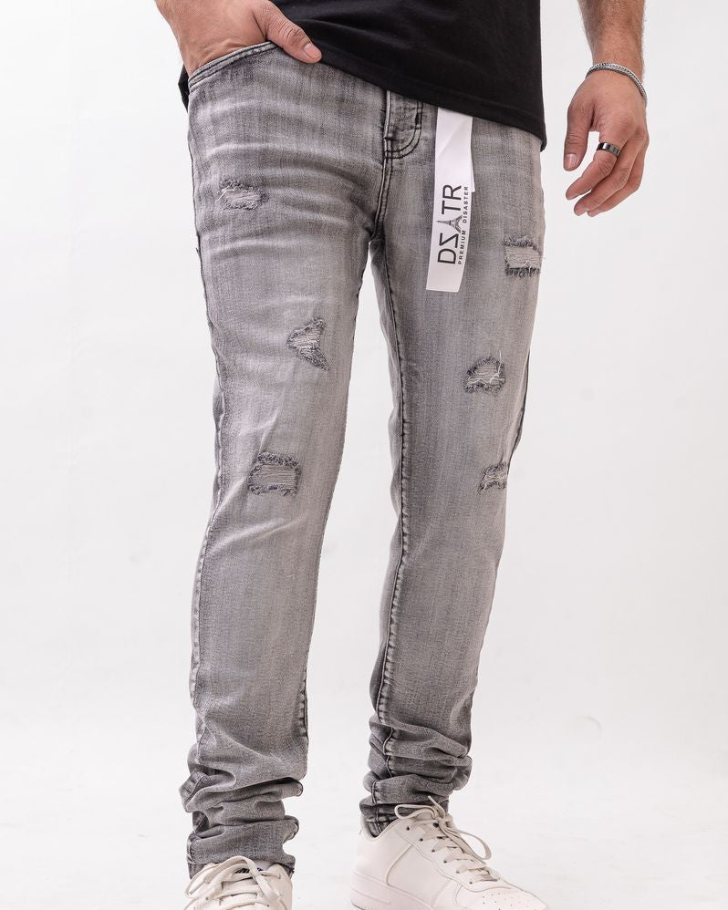 Person wearing gray distressed jeans with a brand label on a white background
