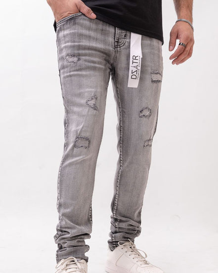 Person wearing gray distressed jeans with a brand label on a white background