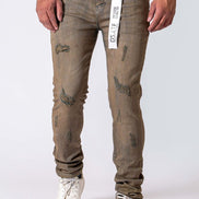 A person wearing distressed brownish-gray slim-fit jeans with a white t-shirt and white sneakers, shown from the waist down against a light gray studio background. A hangtag is visible at the waistband.