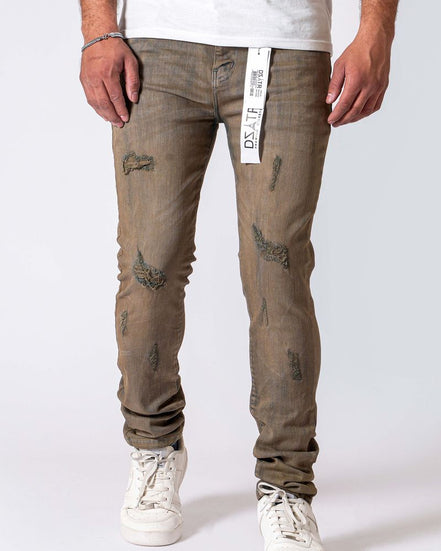 A person wearing distressed brownish-gray slim-fit jeans with a white t-shirt and white sneakers, shown from the waist down against a light gray studio background. A hangtag is visible at the waistband.