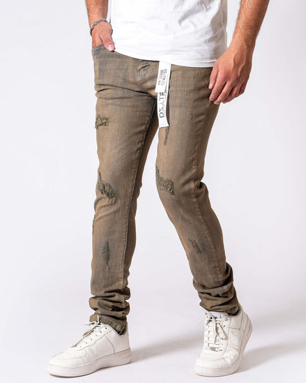 Person wearing beige distressed jeans and white sneakers on a white background
