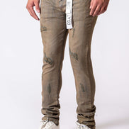 Person wearing beige distressed jeans with a white background