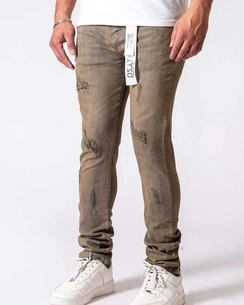 Person wearing beige distressed jeans with a white background