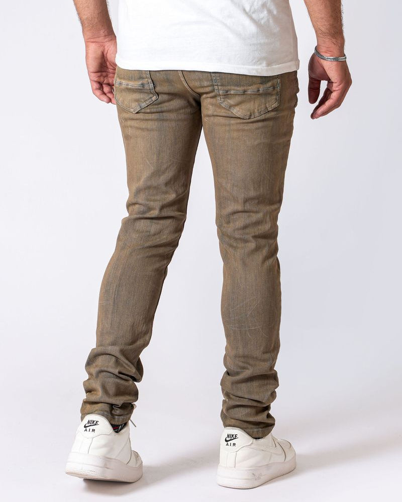 Person wearing brown jeans and white sneakers on a white background