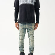 Person wearing a black long-sleeve shirt with white pattern and light blue jeans on a white background