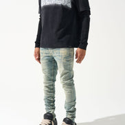 Person wearing a black sweater with white pattern and light blue jeans on a white background