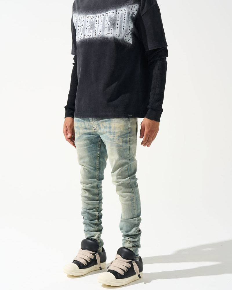 Person wearing a black sweater with white pattern and light blue jeans on a white background