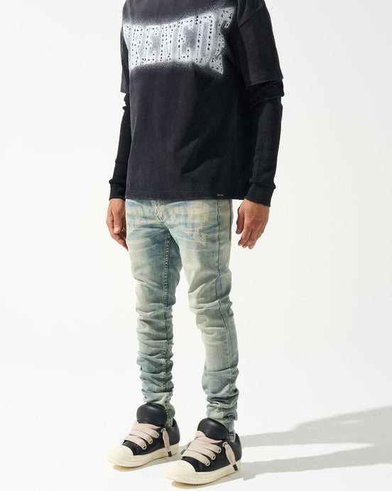 Person wearing a black sweater with white pattern and light blue jeans on a white background
