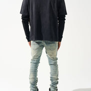 Person wearing a black long-sleeve shirt and light blue jeans on a white background