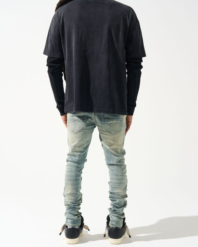Person wearing a black long-sleeve shirt and light blue jeans on a white background